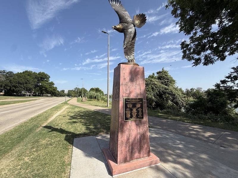 Bronze bald eagle sculpture landing with outstretched wings beside the Brazos River on the Waco Sculpture Zoo trail
