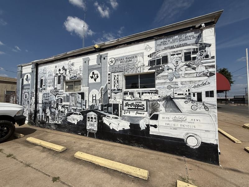 Greyscale This Is Bear County mural in downtown Waco: a roaring bear bursts through boards beside a painted newspaper headline from the 1953 tornado