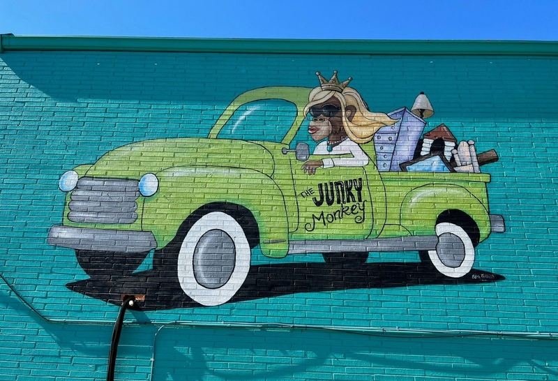 The Junky Monkey mural by Becky Kindred on La Salle Avenue in Waco — a monkey in a crown and blonde wig driving a lime-green pickup truck loaded with furniture